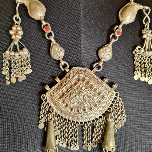 A collection of traditional Kashmiri jewelry, including intricately designed necklaces, earrings, bangles, and headpieces adorned with colorful gemstones and intricate filigree work.